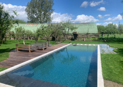 ecozwembad met houten terras langs boomgaard