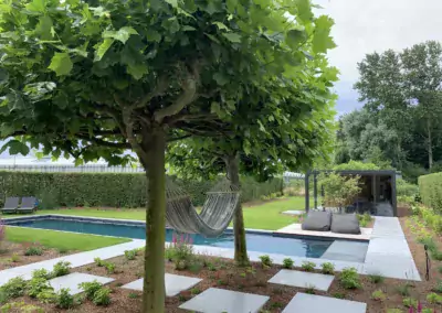 Hybride zwembad in ruime tuin met bomen en hangmat