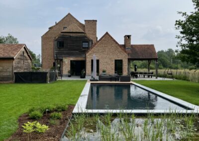 Natuurlijk zwembad met plantenzone en terras in landelijke tuin
